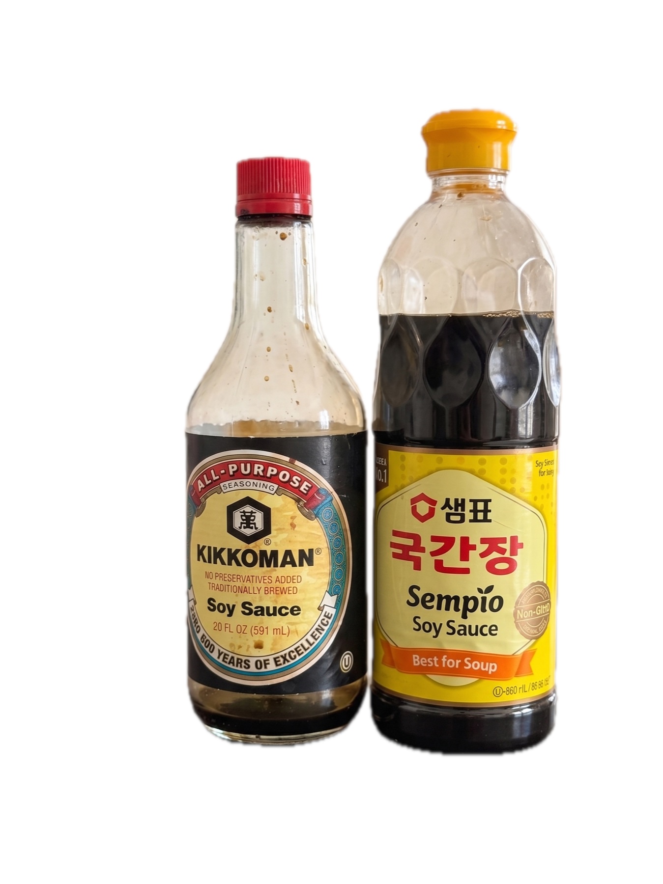 A bottle of Japanese Kikkoman soy sauce beside a bottle of Korean Sempio guk-ganjang against a plain white background